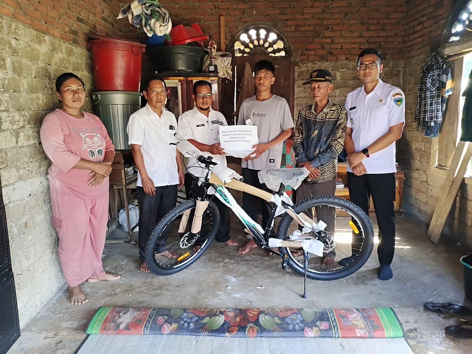 Wali Nagari Punggasan Timur, Tarmizi Lasmeri menyerahkan bantuan sepeda dan perlengkapan sekolah lainnya kepada Pebra. Disaksikan Camat Linggo Sari Baganti, Zul Irfan Harun (kanan) pekan lalu.