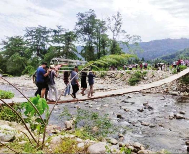 BUTUH SENTUHAN: Warga Nagari Koto Rawang terlihat membawa tandu melintasi jembatan darurat yang hanya layak dilalui pejalan kaki beberapa waktu lalu. (EDI SIKUMBANG UNTUK PADEK)