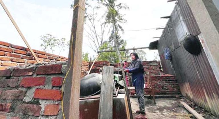 TERDAMPAK: Retno Sriwati menunjukkan kondisi rumahnya yang rusak parah akibat diterjang angin puting beliung beberapa waktu lalu.(SY RIDWAN/PADEK)