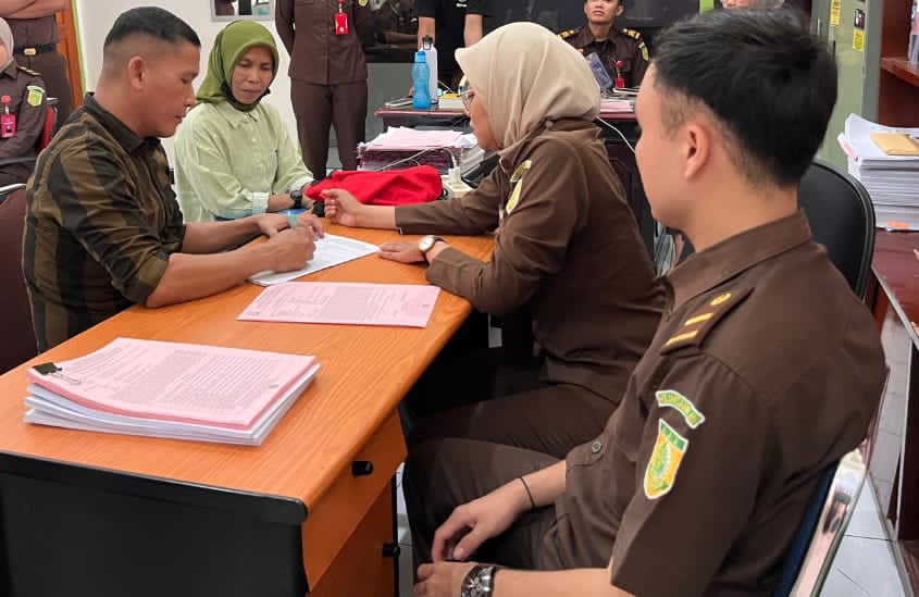 PEMERIKSAAN: Terlihat mantan Wali Nagari Sungai Nyalo IV Koto Mudiek, UA (kiri), saat menandatangani berkas tahap II di Kantor Kejari Pesisir Selatan.(DOKUMEN HUMAS KEJARI PESSEL)