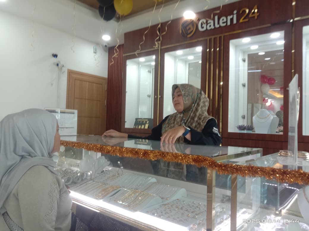 MELAYANI: Seorang pengunjung tengah memperhatikan jajaran emas yang dipajang dalam etalase kaca Galeri 24 di Pegadaian Cabang Padang.(NOVITRI/PADEK)