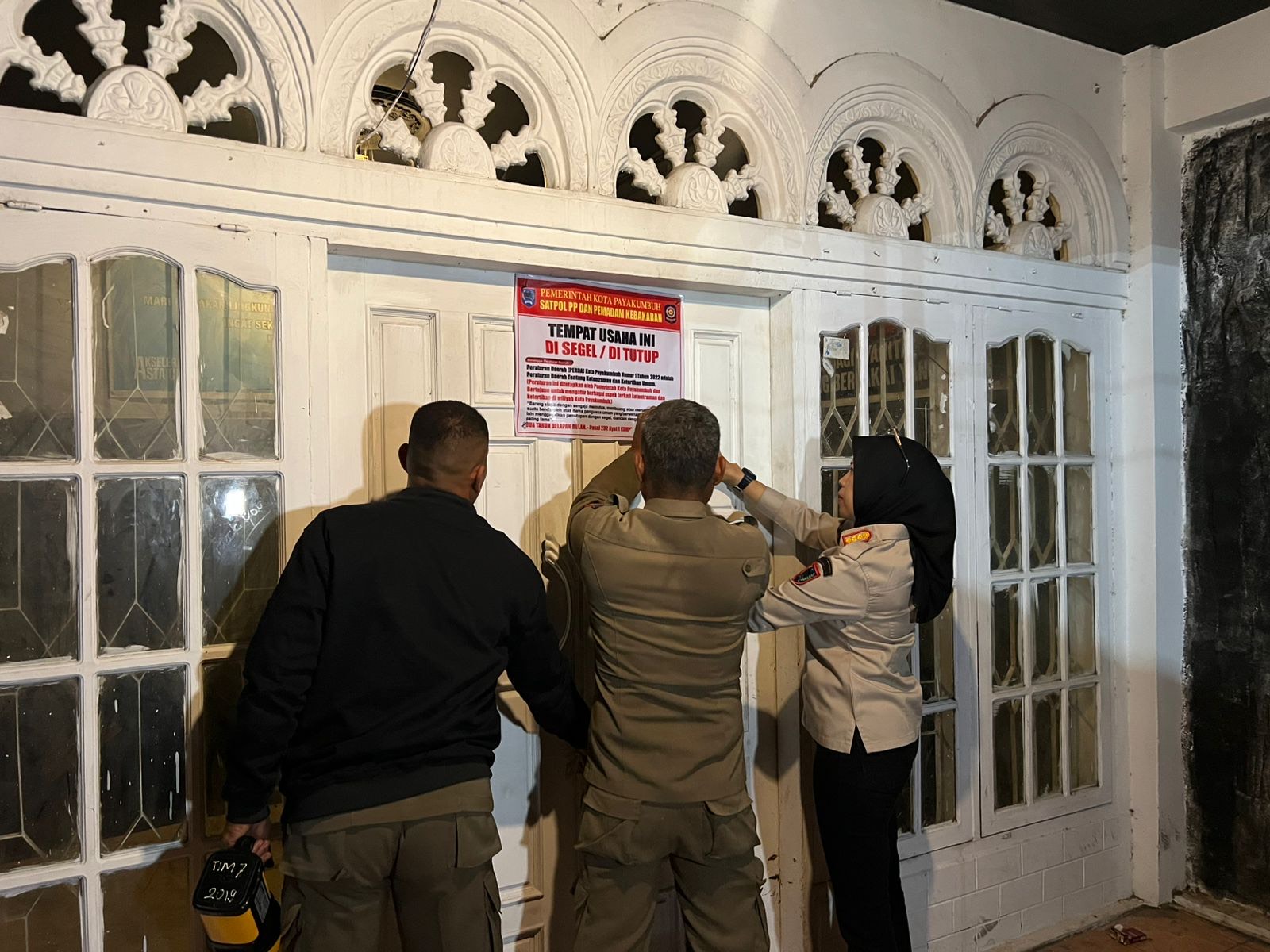 MELANGGAR: Petugas Satpol PP Kota Payakumbuh memasang spanduk penyegelan di salah satu tempat hiburan malam di kawasan Ngalau, Sabtu (30/8) dini hari.