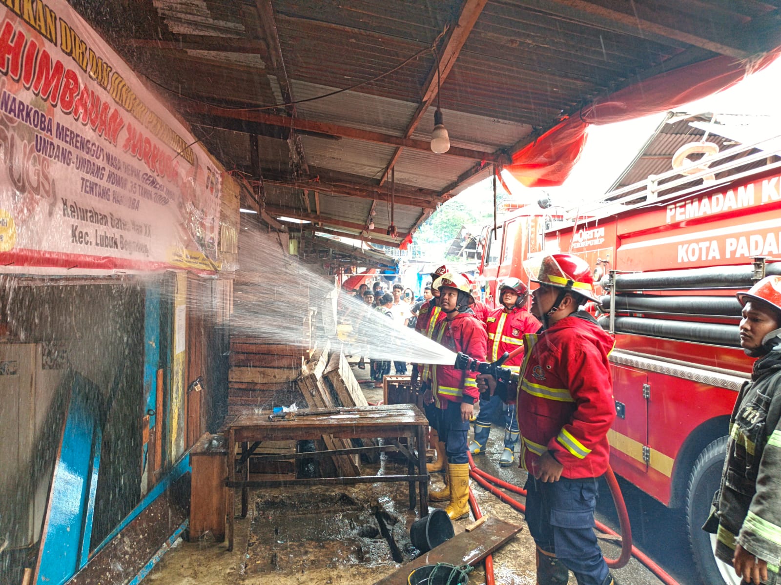 Petugas pemadam kebakaran menyemprotkan air pada sisa-sisa kebakaran yang terjadi di Lubeg, Senin sore.