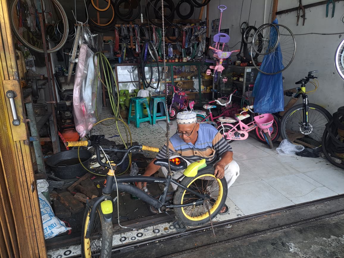 Rustam, pria 60 tahun di Padang, tetap menghidupkan bengkel sepeda sederhana yang sudah berdiri 15 tahun, melayani warga sekitar.