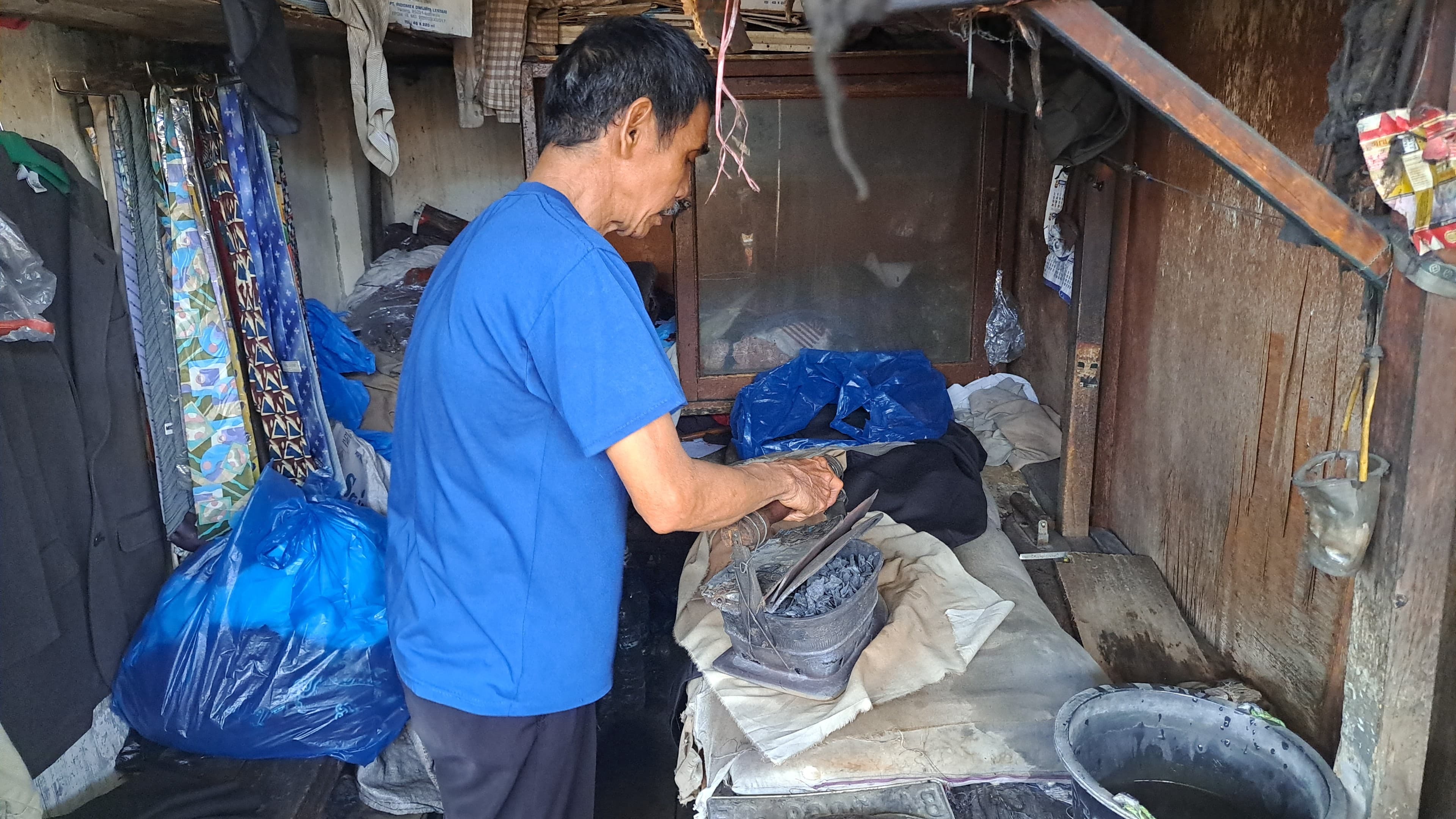 Rul Tanjung saat menyetrika pakaian pelanggang menggunakan setrika arang di Pasar Raya Padang, kemarin