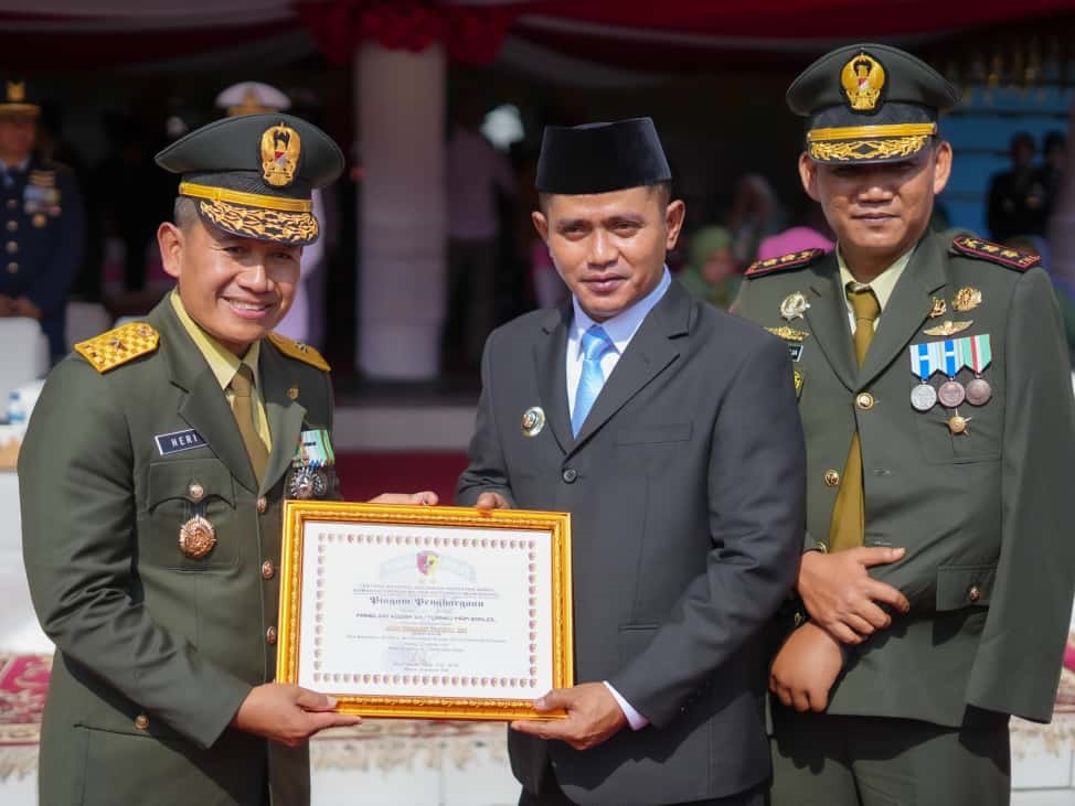 APRESIASI: Bupati Solok Jon Firman Pandu menerima penghargaan dari Kasdam XX Tuanku Imam Bonjol, Brigjen TNI Heri Prakosa Ponco Wibowo, pada peringatan HUT TNI ke-80 di Lapangan Imam Bonjol, Padang.
