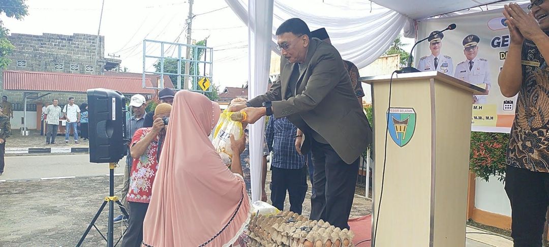 Bupati Pessel, Hendrajoni menyerahkan beras kepada masyarakat yang ikut berbelanja pada GPM di halaman Kantor Camat Lengayang, Kamis (16/10).