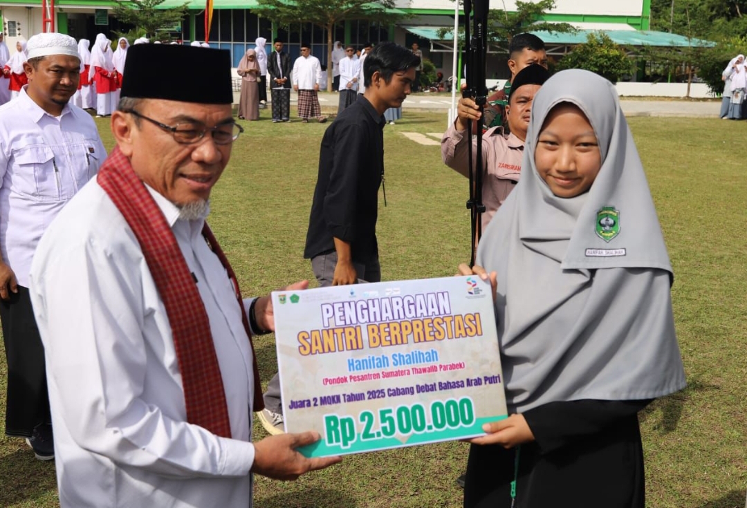 Wakil Wali Kota Padang, Maigus Nasir, menyerahkan penghargaan kepada santri berprestasi dalam acara peringatan Hari Santri Nasional 2025. (Foto: Prokopim)