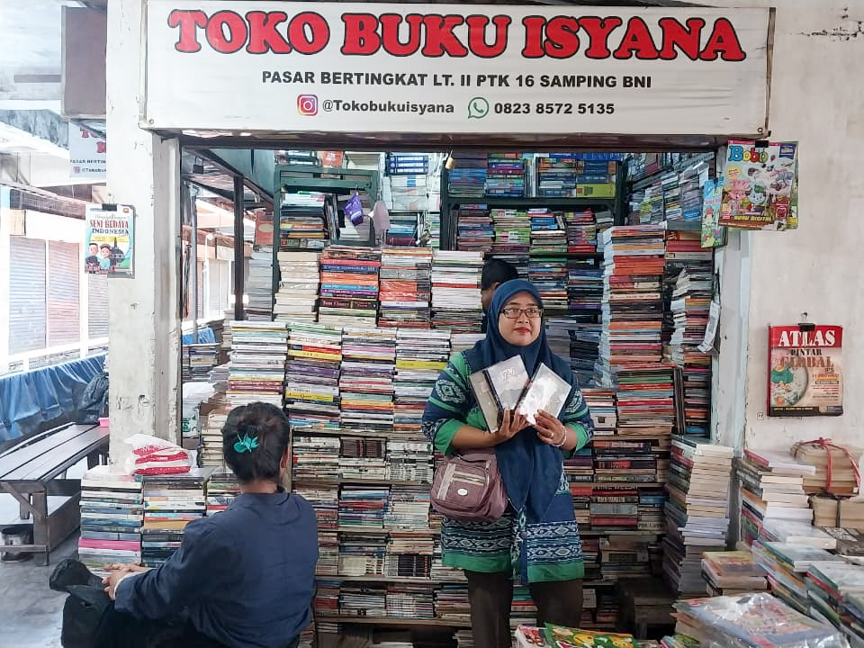 Vivi memperlihatkan beberapa buku koleksi di toko buku Isyana yang ia kelola bersama suaminya, Tomi Ramadhan, di Pasar Bertingkat Lt II Petak 16, Pasar Raya Padang. (Foto: Mengki Kurniawan/Padeks).