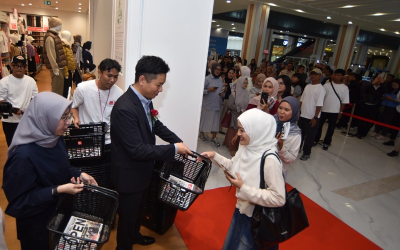 Ryohei Sato, Co-COO PT Fast Retailing Indonesia (UNIQLO Indonesia), memberikan keranjang kepada pengunjung toko UNIQLO di Basko City Mall Padang, Jumat (31/10/2025).