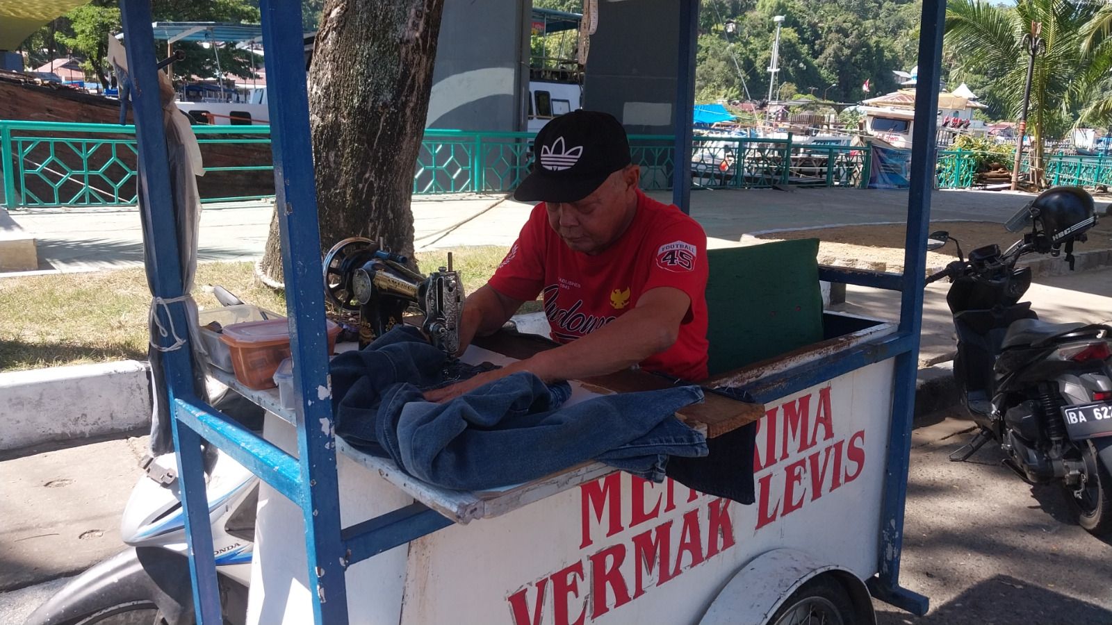 Pak Bram, penjahit jeans di kawasan Batang Arau, sedang memperbaiki jeans pelanggan.
