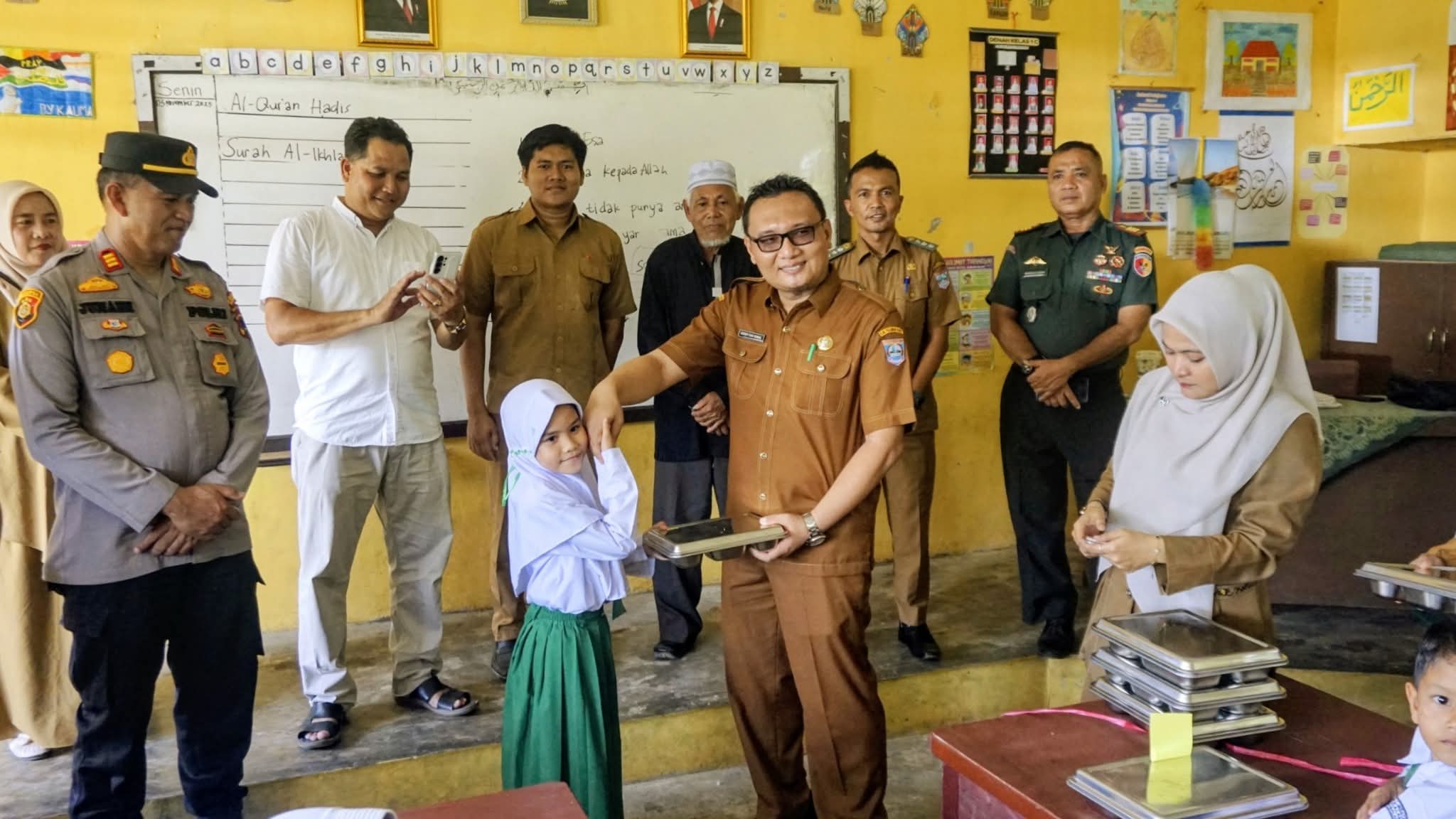 DISALURKAN : Sekkab Pasbar, Doddy San Ismail menyerahkan MBG kepada salah seorang murid SD.