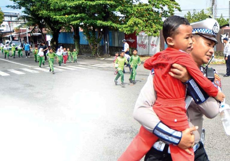 Polisi membantu dan mengarahkan sejumlah pelajar berlari ke arah tempat evakuasi sementara saat digelarnya Tsunami Drill di Padang kemarin (5/11).