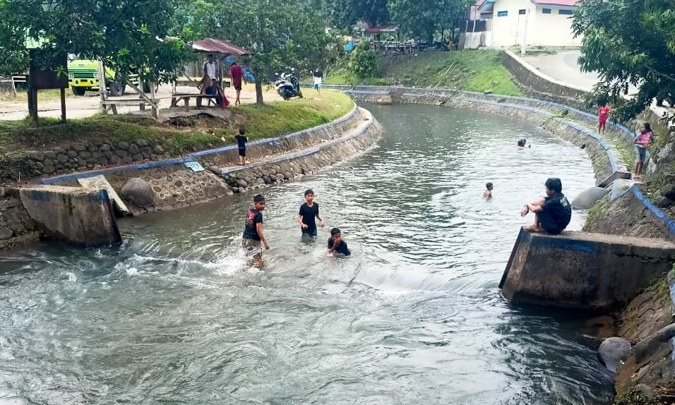 Anak-anak bermain air, mandi-mandi, dan berenang di aliran sungai irigasi Gunung Nago, Jumat sore (07/11/2025). (M Reza Bayu/Padeks)