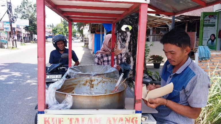 KUE TALAM LEGENDARIS: Ikil Saputra ketika sedang menjajakan kue talam dagangannya di kawasan Jl. Raya Air Dingin, Kelurahan Balai Gadang, Kecamatan Koto Tangah, Kota Padang, (08/11).