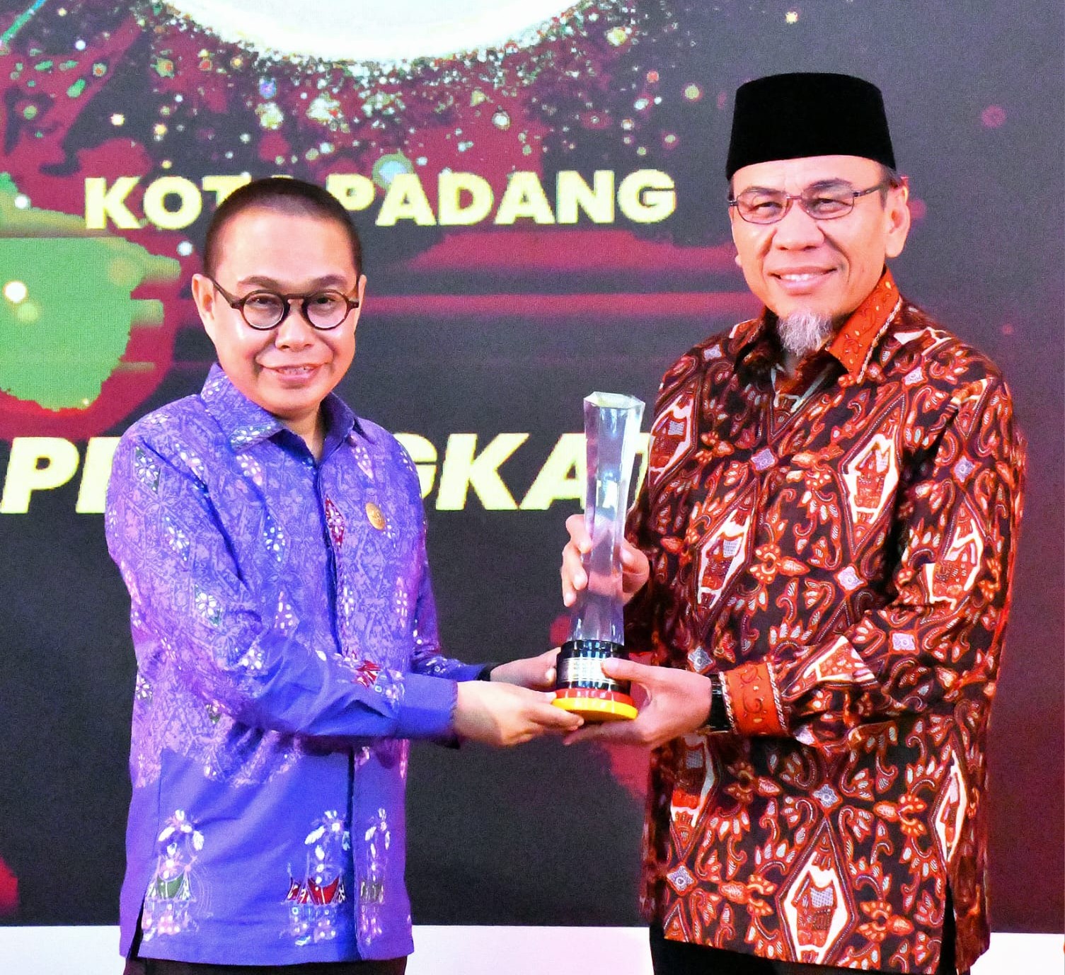 Wakil Wali Kota Padang Maigus Nasir menerima piala peringkat satu KIP 2025 dari Ketua KI Provinsi Sumbar, Musfi Yendra.