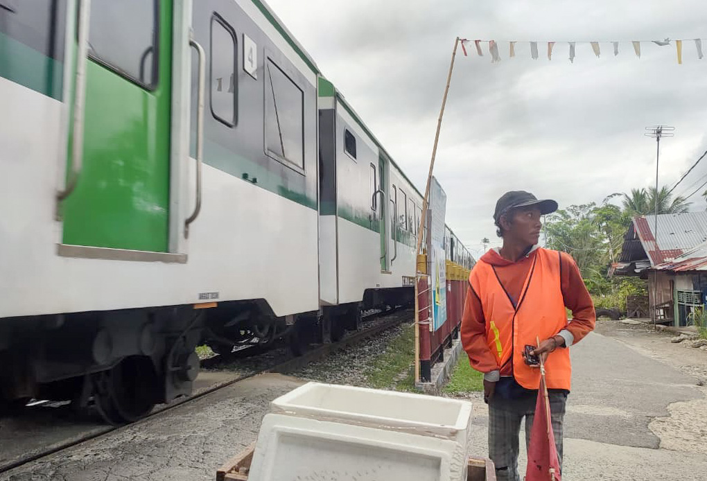 Rizki Rahmad Putra (39) meski dengan keterbatasan fisiknya ia mengatur lalu lintas jalan ketika kereta melintas. (Foto: Riyadhatul Khalbi/Padeks)