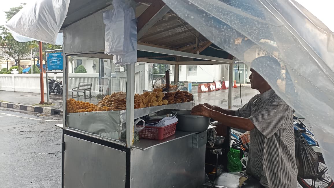 Musim hujan di Padang berdampak pada pedagang gorengan. Penjualan menurun karena pembeli sepi dan aktivitas pasar berkurang. (Foto: Fadli Z/Padeks)