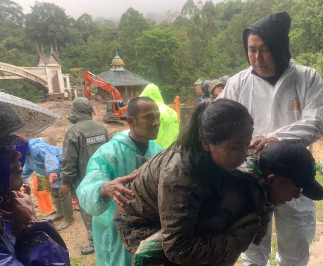 Warga digendong petugas saat proses evakuasi dari lokasi terisolasi akibat longsor dan arus deras.(Foto: Kominfo Padangpanjang)