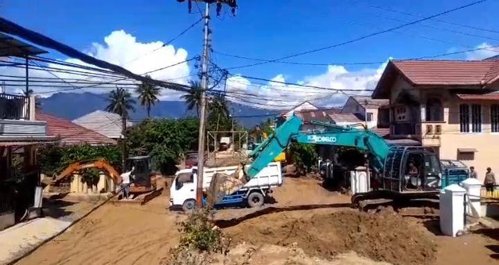 Operator alat berat sedang bekerja membersihkan sedimen yang menumpuk pasca banjir.