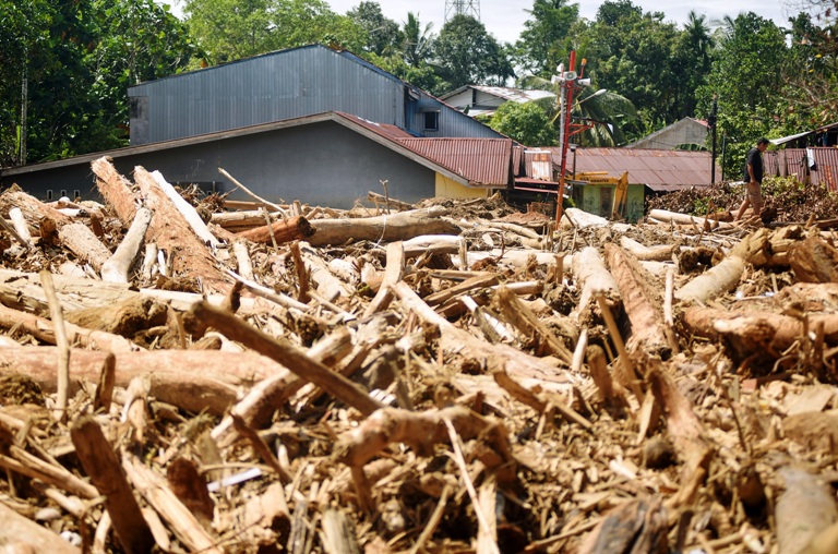 TUMPUKAN KAYU DI PEMUKIMAN Warga melintas di antara tumpukan kayu di pemukiman di Tabiang Bandang Gadang, Kecamatan Nanggalo, Kota Padang, Selasa (9/12).