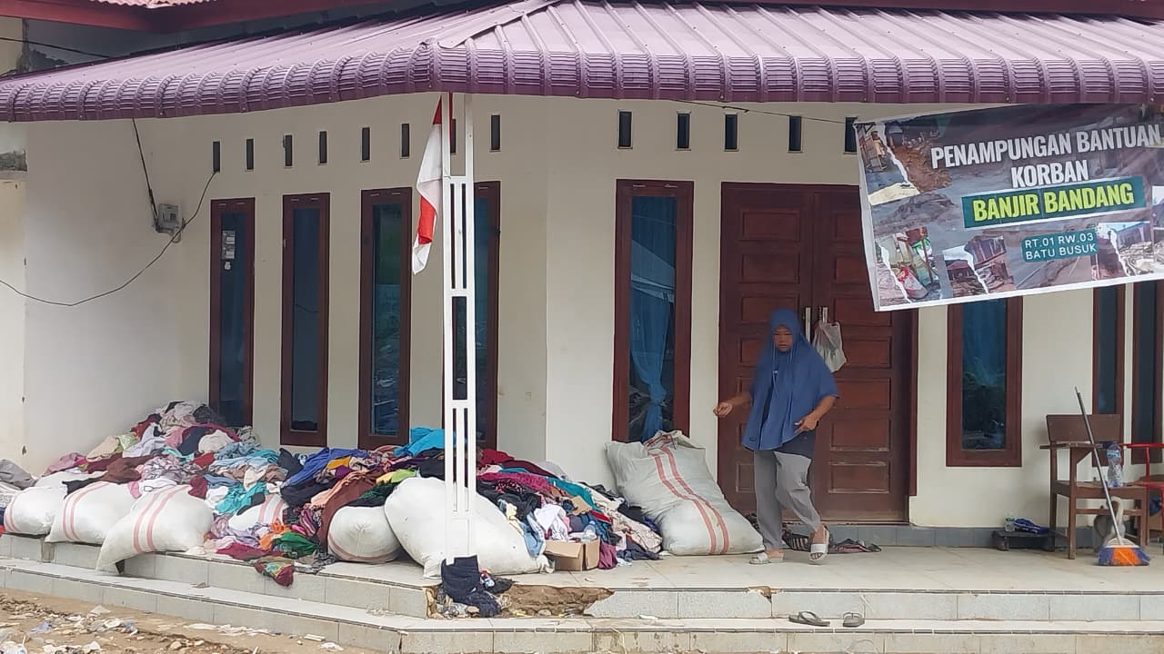 Pakaian bantuan menumpuk di Posko Batu Busuk Padang akibat kelebihan pasokan. Pengelola menegaskan kebutuhan mendesak kini makanan dan air bersih, Senin (15/12/2025). (Foto: Mengki Kurniawan/Padeks)