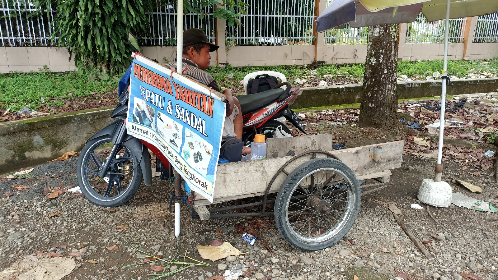 Mawi, tukang sol sepatu keliling, sedang beristirahat di becaknya.