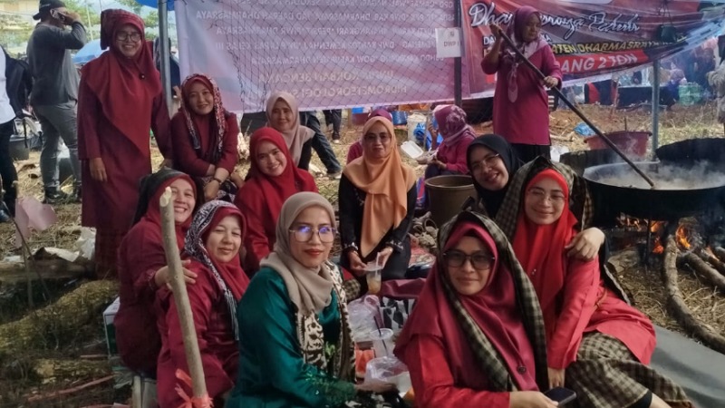 Ibu-ibu DW Kabupaten Dharmasraya dan lainnya tetap semangat memasak rendang di tengah cuaca yang panas yang berasal dari api tungku dan full asap.