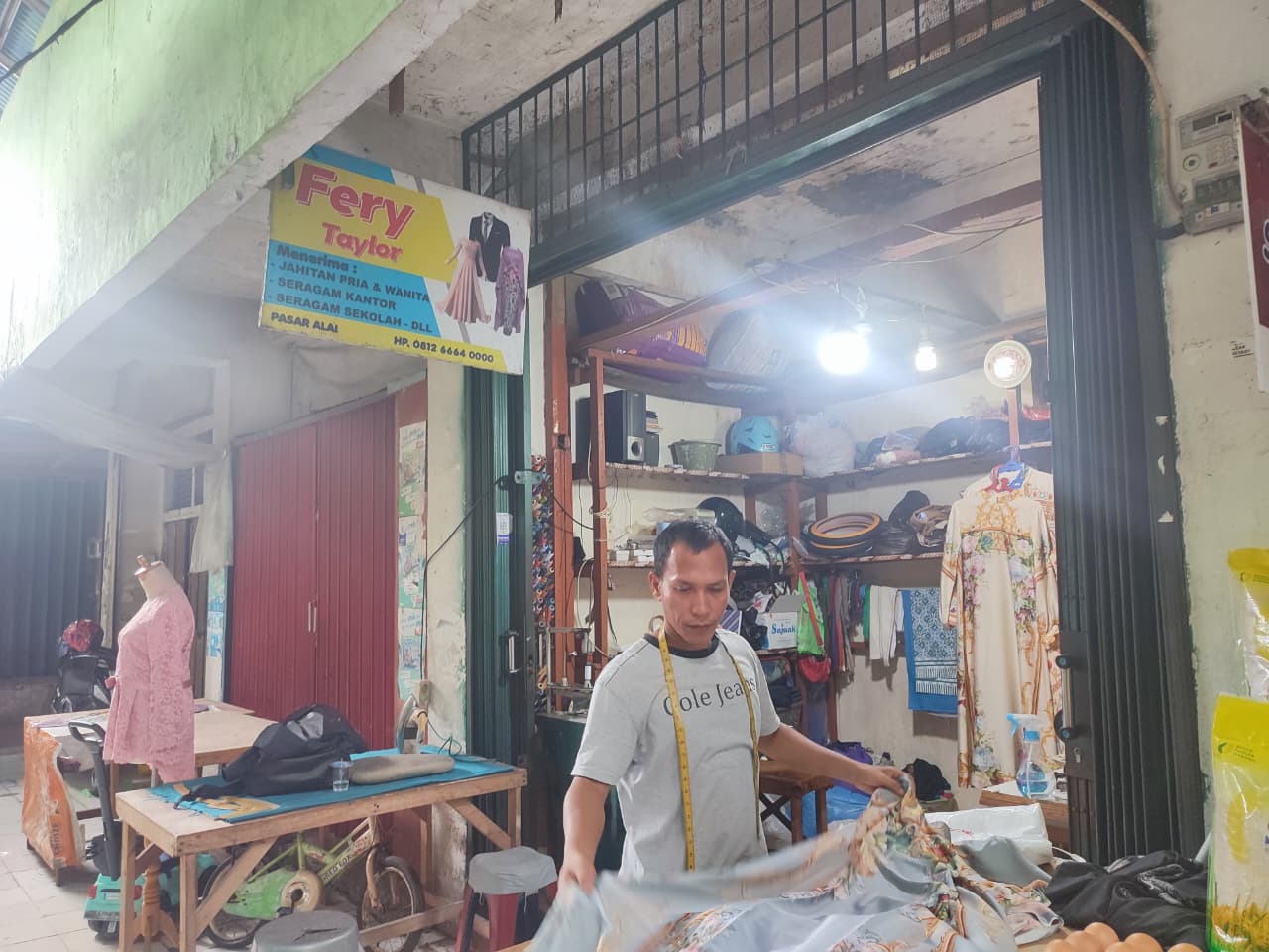 Syafrianto, penjahit di Pasar Alai, sedang mengukur baju pelanggannya beberapa waktu lalu.