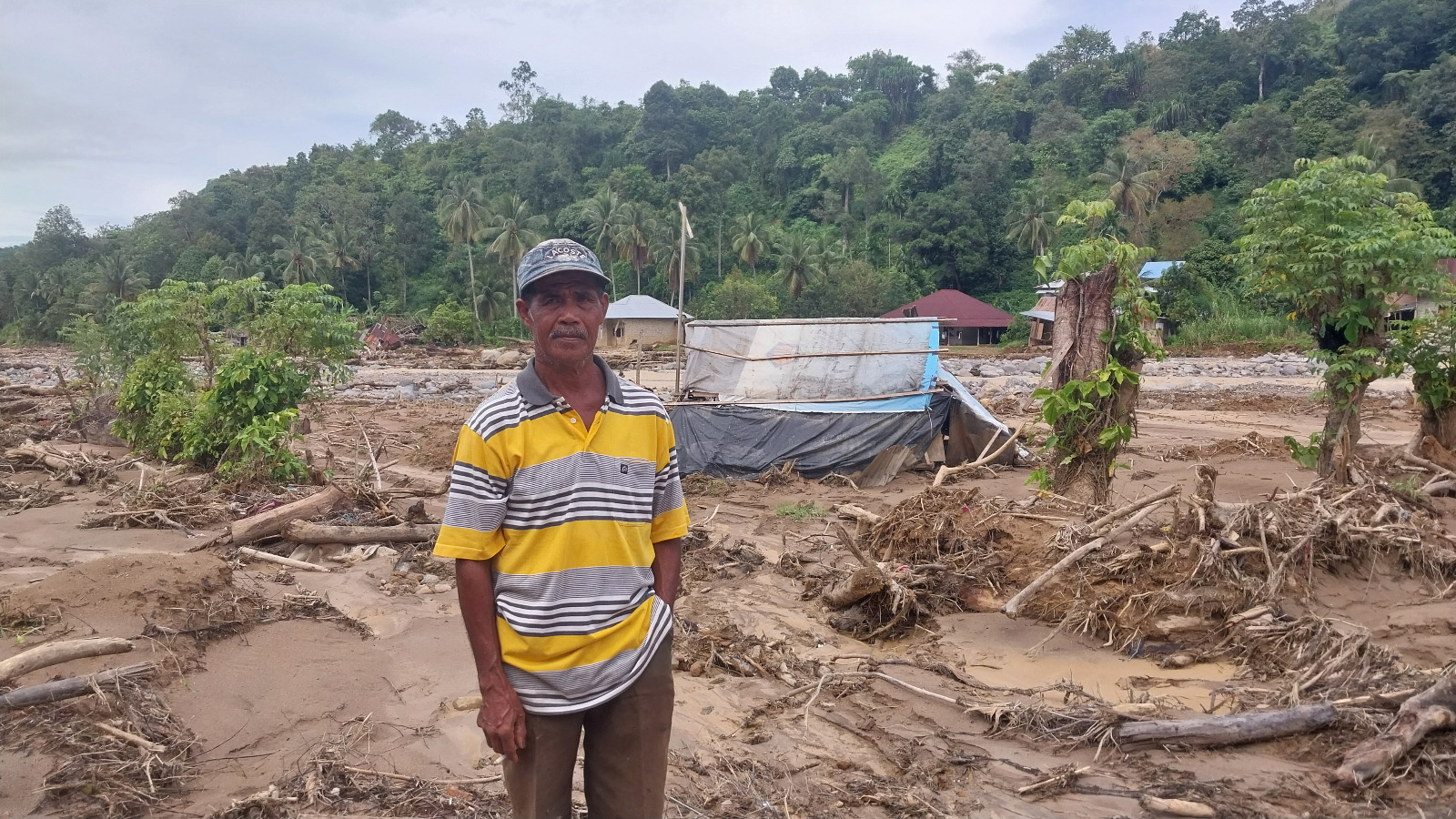Tasar, petani di Batubusuk, berdiri di bekas lahan sawahnya yang rusak diterjang banjir bandang beberapa waktu lalu.