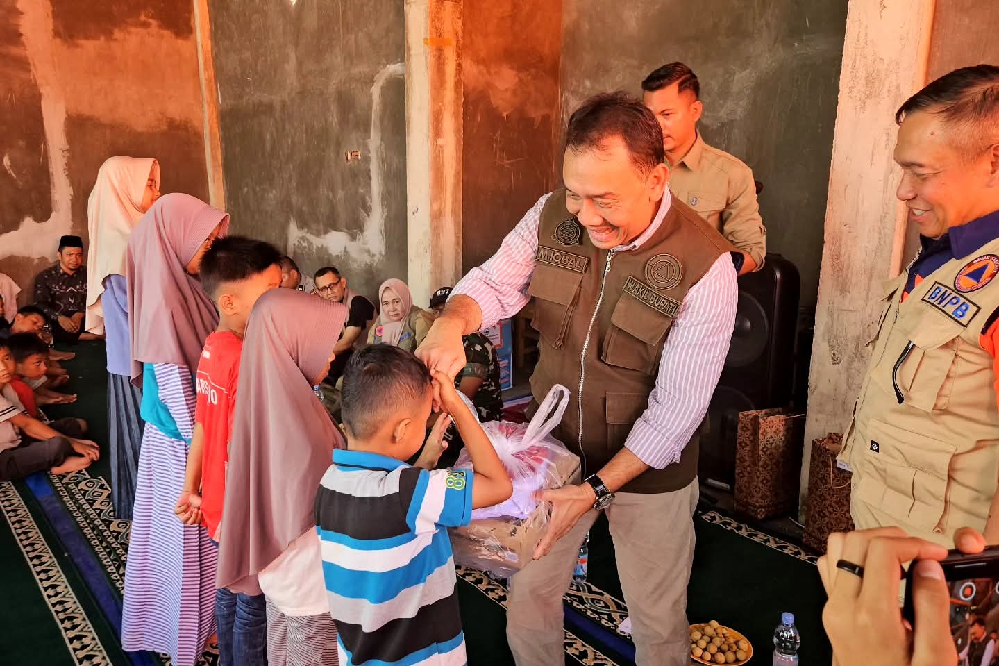 Wabup Agam Muhammad Iqbal menyerahkan bantuan seragam sekolah pada anak-anak korban bencana di Salarehaia, Palembayan, Minggu (4/1/2026).