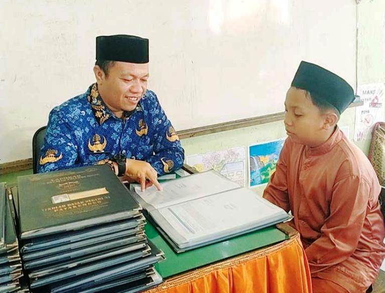 MOTIVASI : Penulis ketika memberikan motivasi kepada salah seorang murid SDN 31 Payakumbuh untuk terus giat berlajar demi mencapai nilai yang bagus.