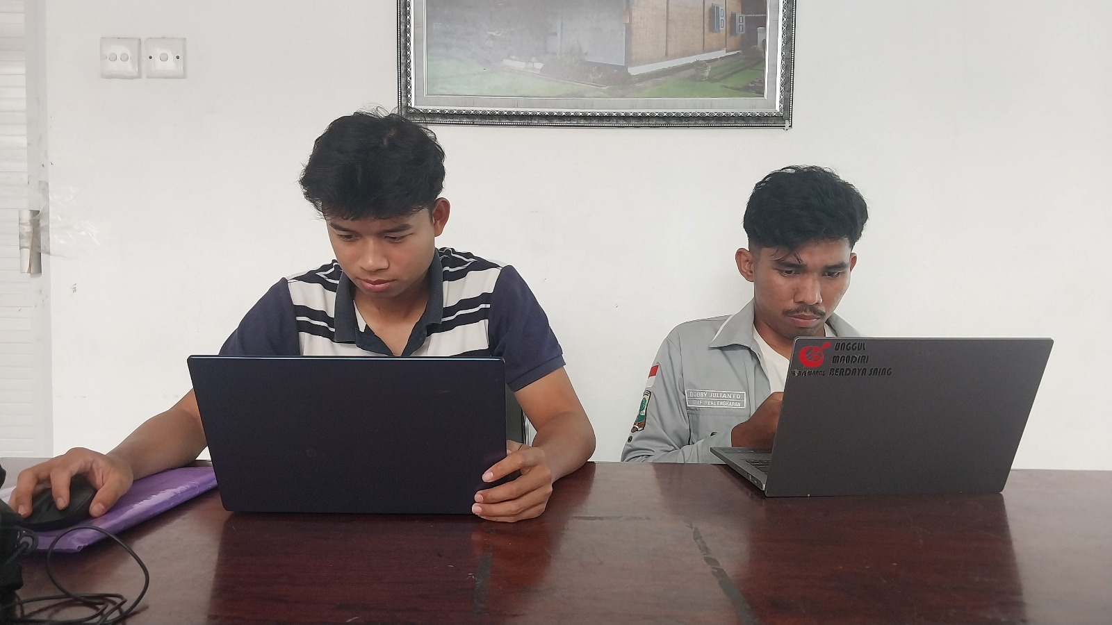 Dua orang mahasiswa tengah serius mengerjakan tugas mereka.