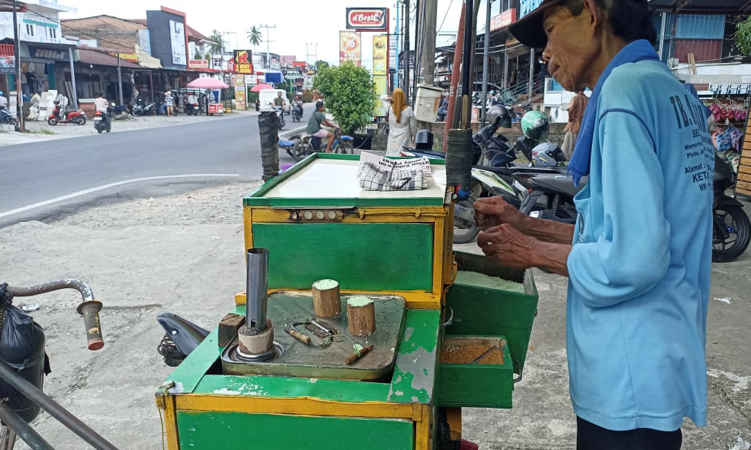 Pak Sulam, penjual kue putu 66 tahun di Simpang Empat, Pasaman Barat, yang bertahan berjualan demi keluarga dengan sepeda tuanya.(Foto: Fadli Zikri/Padeks)