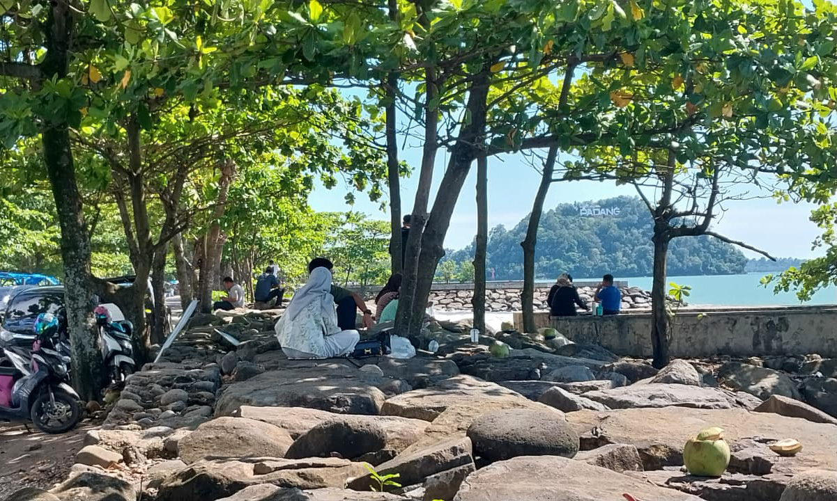 Cuaca terik di Kota Padang tak mengurangi kunjungan ke Pantai Padang. Pohon pelindung di Taplau menjadi tempat favorit warga untuk berteduh pada Minggu (11/1/2026) siang. (Ft: Mengki Kurniawan/Padeks)