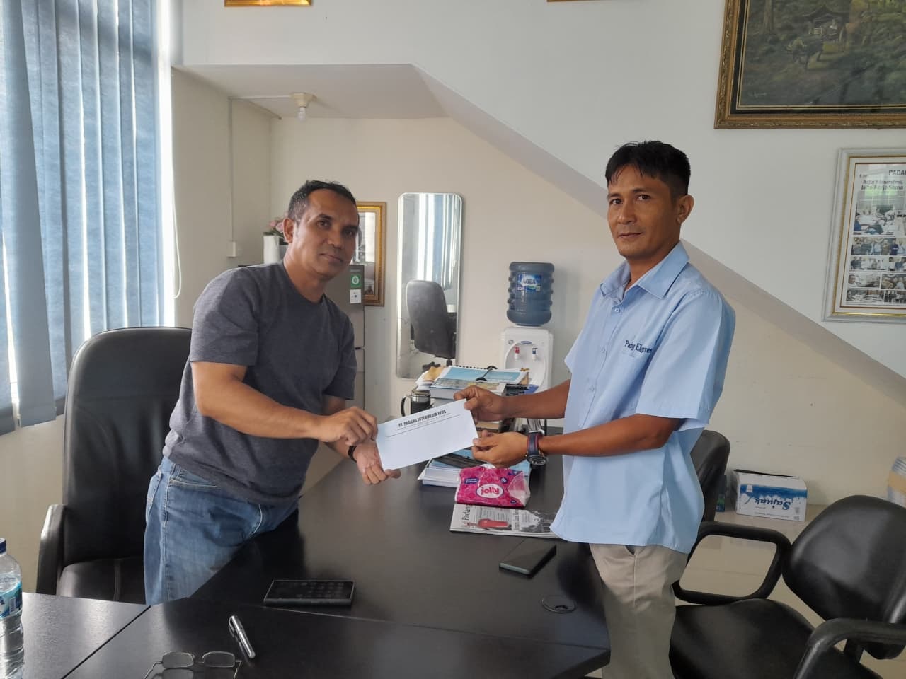 Dirut Padang Ekpres, Mhd. Nazir Fahmi memberikan penghargaan dan hadiah kepada pemenang desain logo HUT ke-27 Padang Ekspres, Feri Agus Sumantri, kemarin.