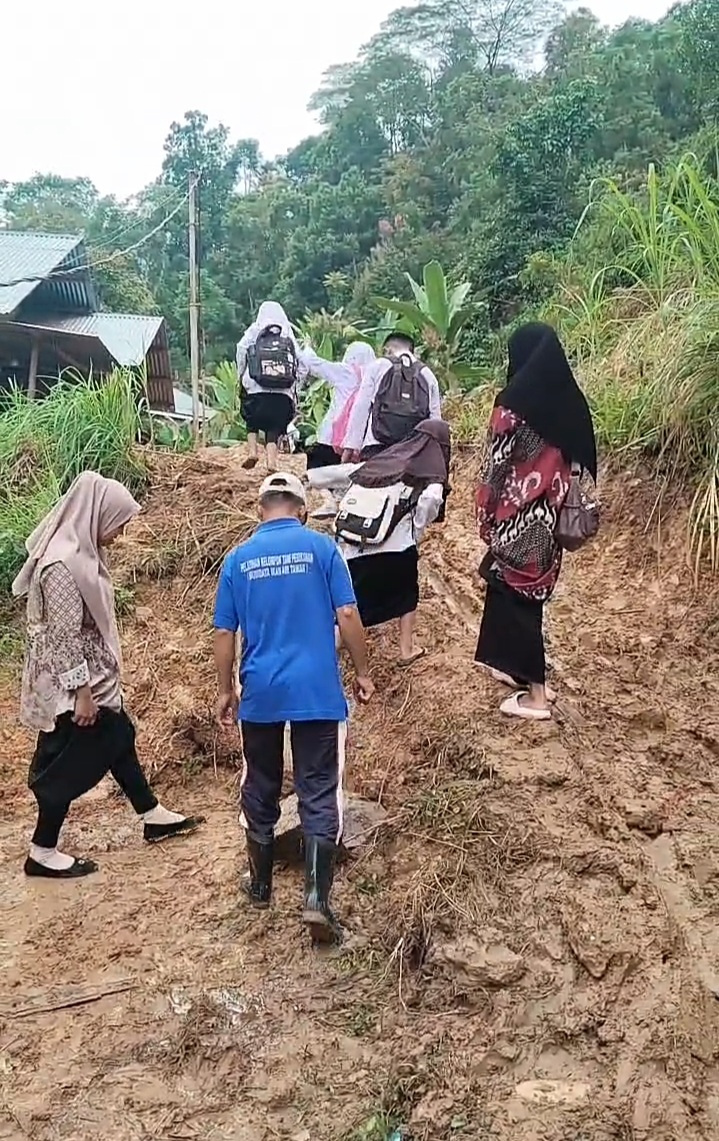 Para siswa dan guru berjalan kaki menerobos jalan berlumpur untuk menuju sekolah mereka di Nagari Ngalau Gadang.