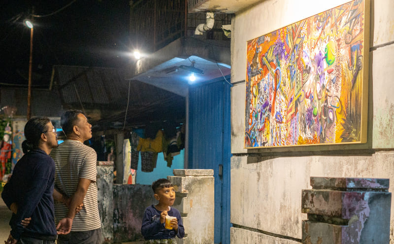 Yulviadi mengamati karya seni lukisan di dinding pameran "Ke Rumah Nan Tumpah #10" di Korong Kasai, Padangpariaman.(Foto: Komunitas Seni Nan Tumpah)