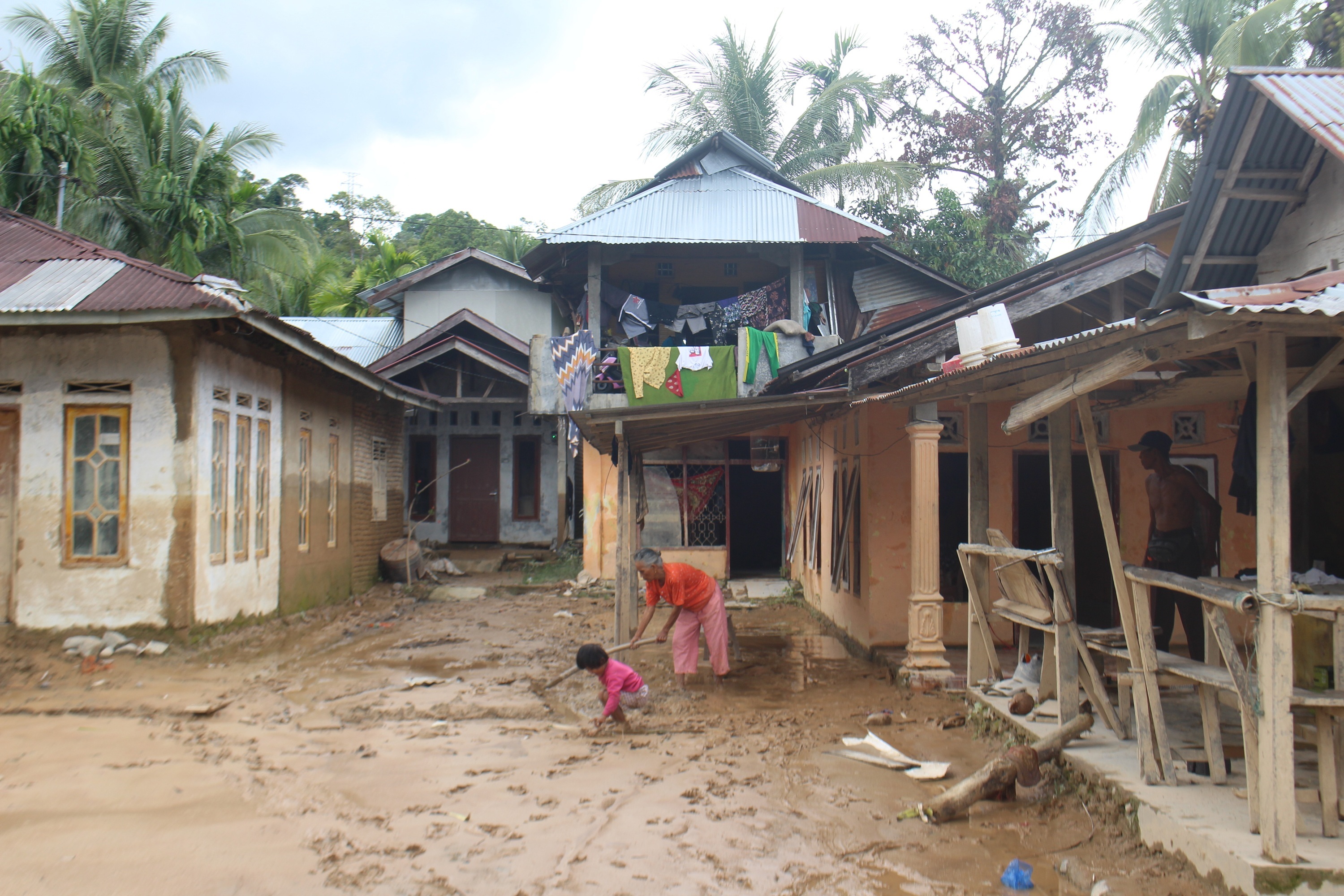 BERUSAHA KERAS: Salah seorang warga di Korong Tanahtaban, Nagari Pasia Laweh Lubuak Aluang saat membersihkan rumahnya dari lumpur yang dibawa oleh banjir bandang, kemarin.