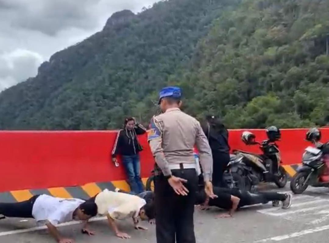 Petugas Satlantas Polres Limapuluh Kota menindak pengendara yang parkir sembarangan di Flyover Kelok Sembilan dengan sanksi push up saat operasi pengamanan arus mudik Ramadan 1447 H.(Foto: Satlantas)