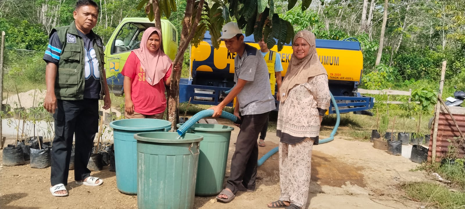 Wali Nagari Ampek Koto Pulaupunjung David Iskan didampingi anggota BPBD  Syafrimas dan Camat Pulaupunjung Erik Harja mengisi langsung air ke  ember warga.