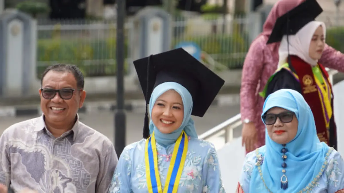 Orang tua bersama anaknya yang mengenakan toga setelah prosesi pengukuhan pada hari kedua Wisuda ke-142 Universitas Negeri Padang (UNP) di pelataran Auditorium UNP, Padang, Senin (6/4/2026). (Foto: Humas)