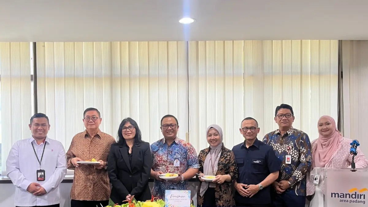 Direktur Retail Mandiri Sekuritas Theodora V.N. Manik memyerahkan potongan tumpeng kepada Area Head Bank Mandiri Padang Feri Cahyono saat peresmian Investment Corner.(Foto: Corcom)