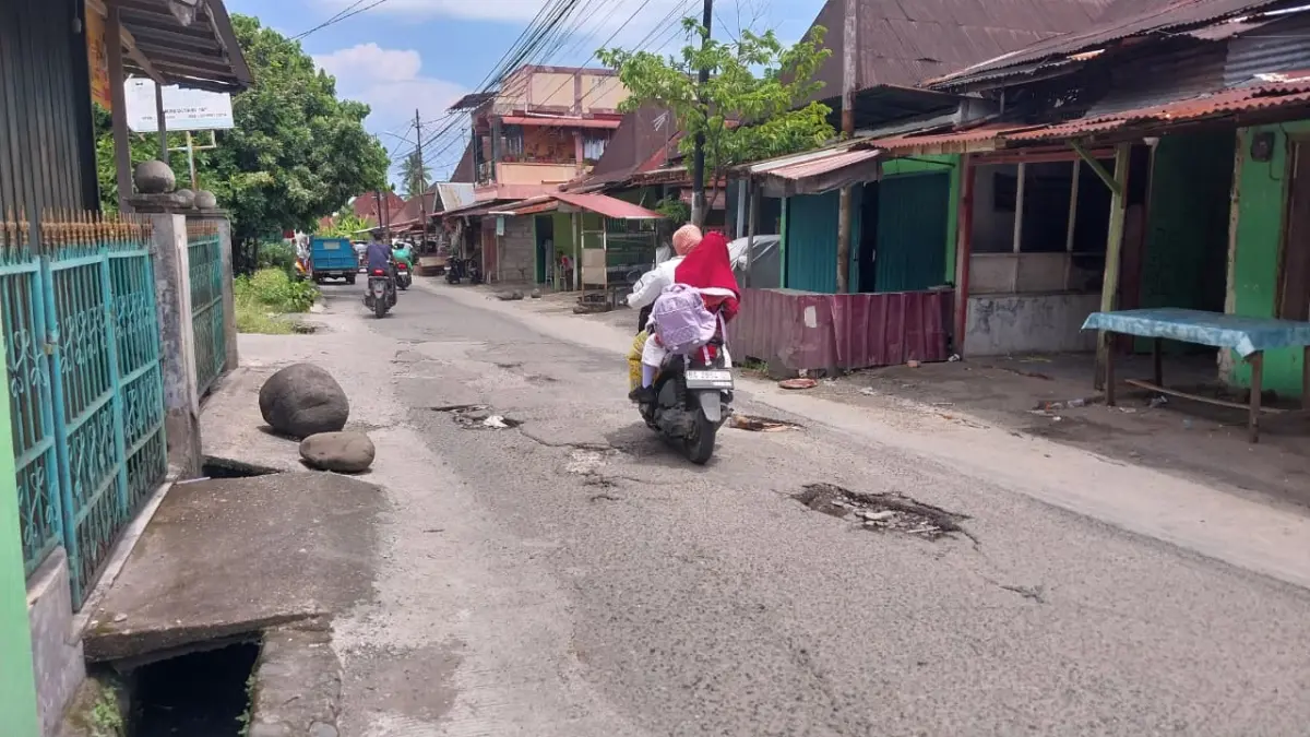 Salah seorang pengendara sepeda motor melintasi Jalan Pisang di Kelurahan Cupak Tangah, Kecamatan Pauh yang dipenuhi lubang, Selasa (14/4/2026). (MENGKI/PADEK)