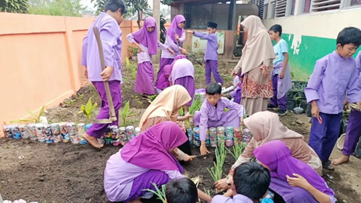 Siswa SD Negeri 55 Payakumbuh sedang menanam tanaman apotik hidup  ditemani ibu guru di belakang sekolah beberapa waktu lalu. (TIM LAMAN GURU)