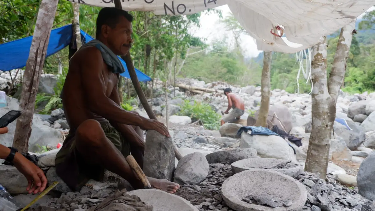 Jamalis (Buyuang Manggih) salah seorang Pengrajin Cobek Batu di kawasan Bendungan Limau Manis, Pauh, Padang ketika memahat batu cobek, Rabu (15/4/2026). (MENGKI/PADEK)