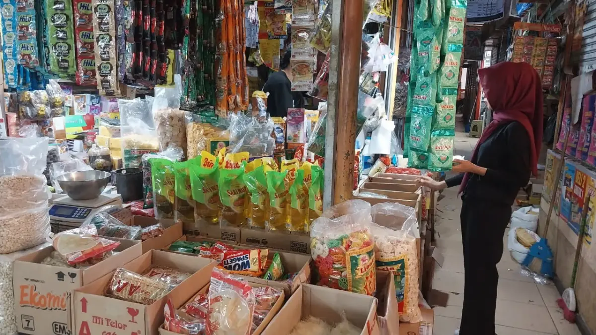 Salah satu pemilik kedai sembako di Pasar Raya Padang mengonfirmasi kenaikan mayoritas sembako dan bahan dapur, Minggu (19/4/2026). (Foto: Mengki Kurniawan/Padeks)