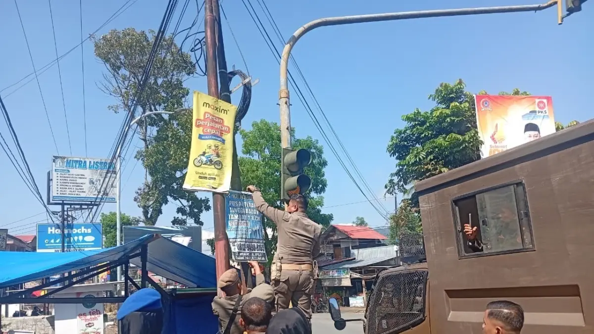 Anggota Satpol PP Kota Payakumbuh membersihkan reklame yang terpasang di tiang, Rabu (22/4). (DOK SATPOL PP PAYAKUMBUH)

