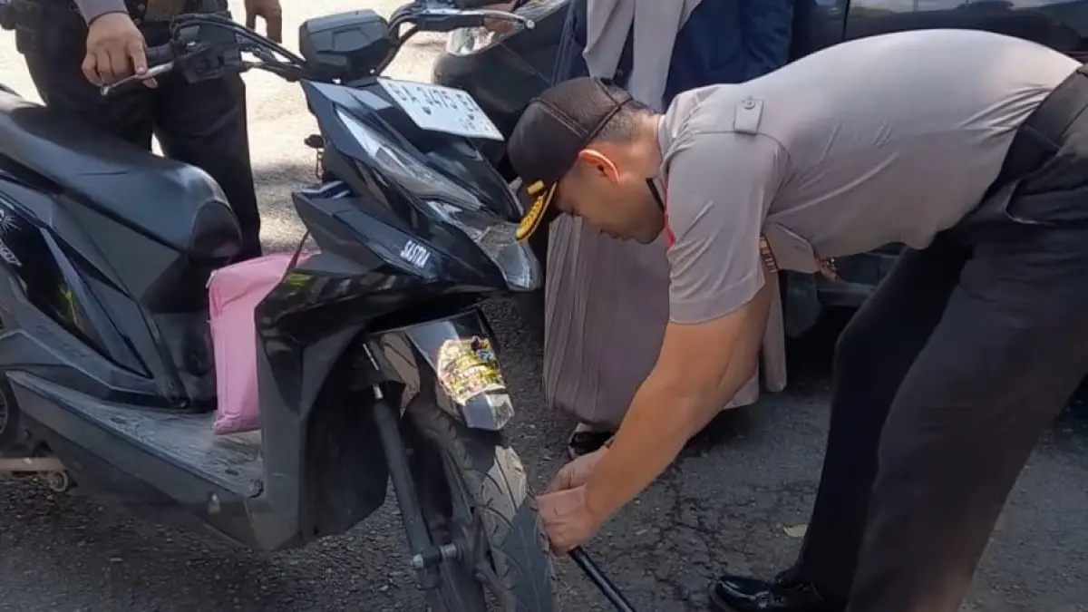 Kapolres Tanahdatar AKBP Nur Ichsan Dwi Septiyanto memasang kunci ganda pada sepeda motor pengendara saat kegiatan di depan Lapangan Cindua Mato, Batusangkar, Senin (27/04/2026).