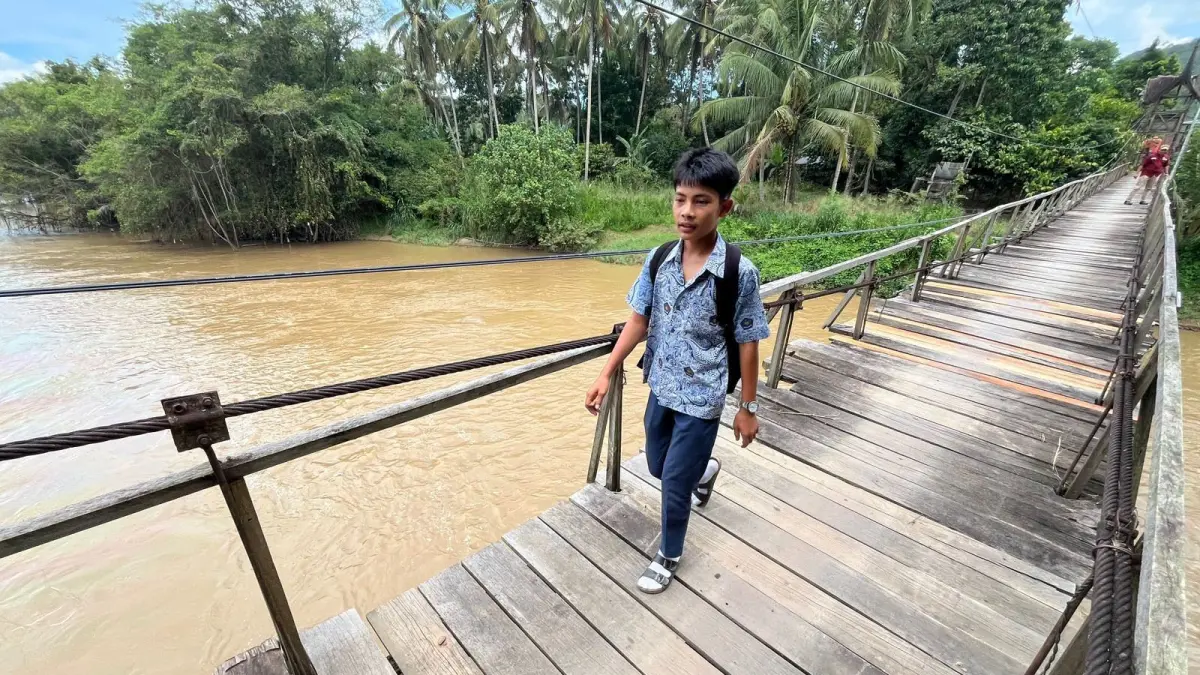 Seorang siswa sedang melewati jembatan Gantung Sawahgadang yang sudah mulai rapuh, Senin (4/5). (SY RIDWAN/PADEK)